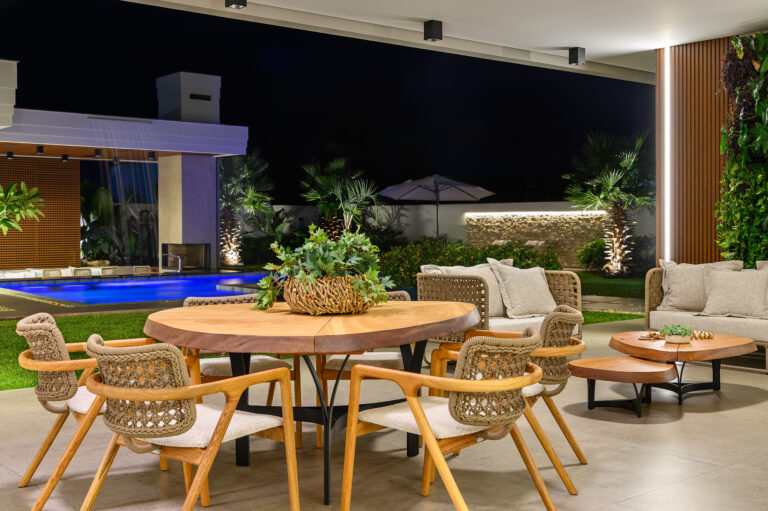 Área de lazer com mesa redonda e piscina à noite – projeto i9 Arquitetura